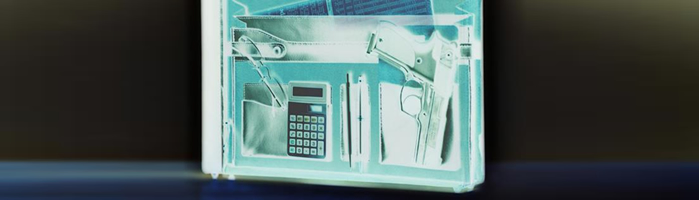 TSA checkpoint x-ray reveals firearm inside briefcase. x-ray picture of briefcase reveals a gun, calculator, glasses and other office supplies inside.